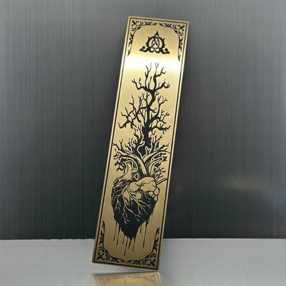 A gold metallic acrylic bookmark with a heart with a tree growing out of it.