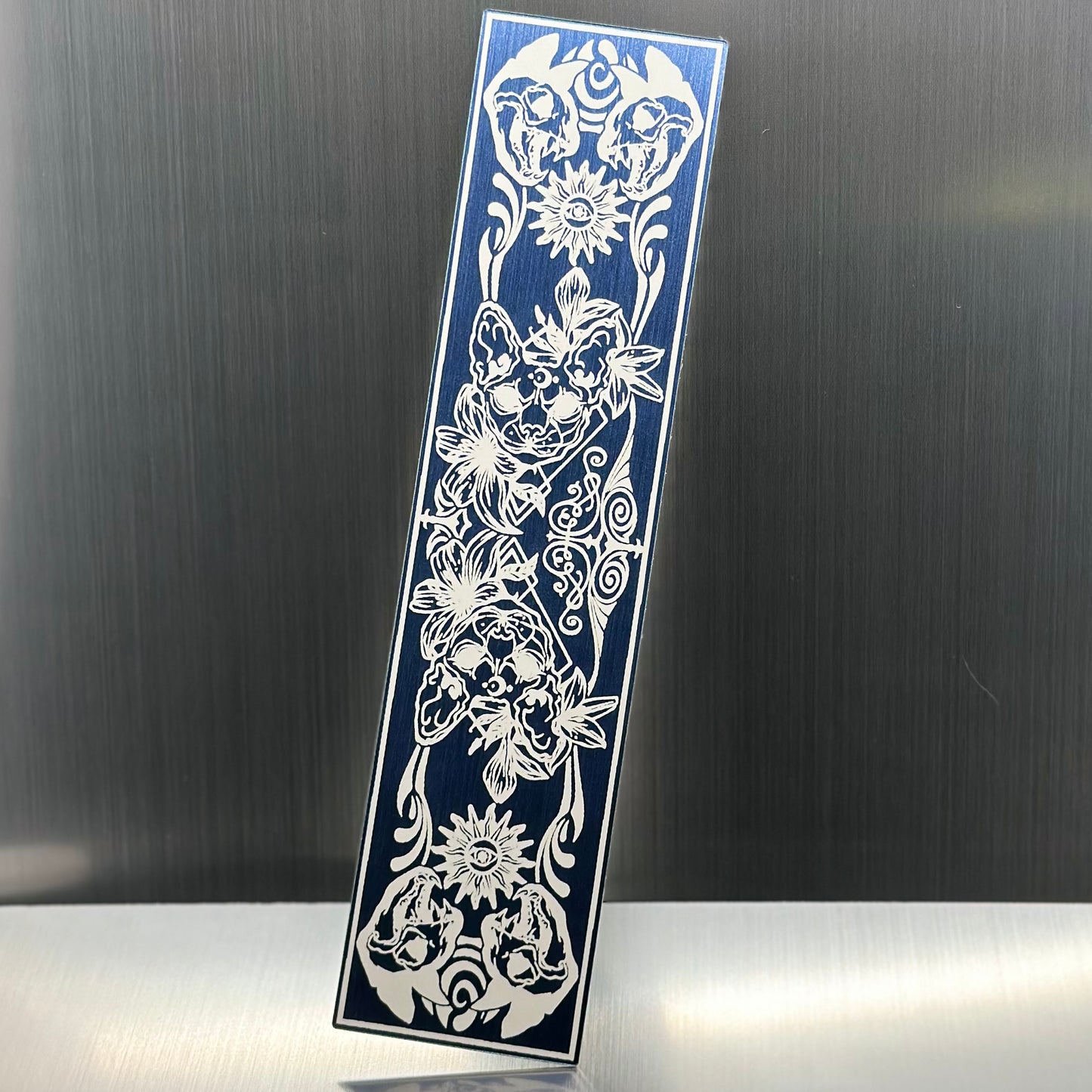 A blue metallic acryclic bookmark with cat skulls