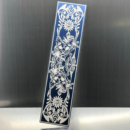 A blue metallic acryclic bookmark with cat skulls