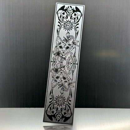 A silver metallic acryclic bookmark with cat skulls
