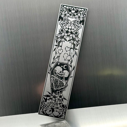 A silver metallic acrylic bookmark with skeletons embracing