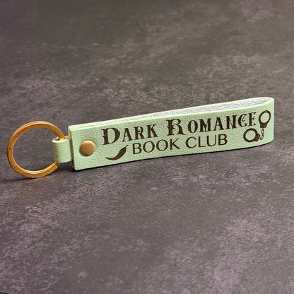 A matcha green faux-leather keychain with 'Dark Romance book club' etched into it.