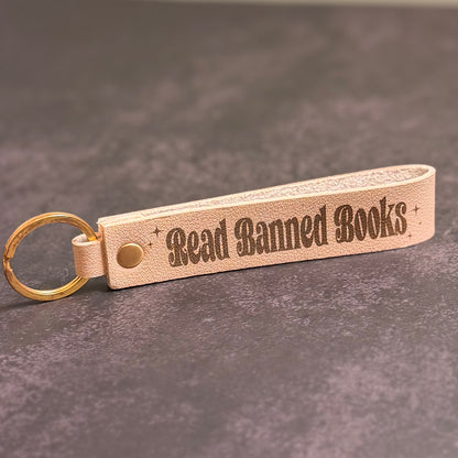 A beige faux-leather keychain with 'Read Banned Books' etched into it.