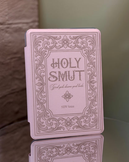 Kindle case with 'Holy Smut' text and decorative border on a reflective 