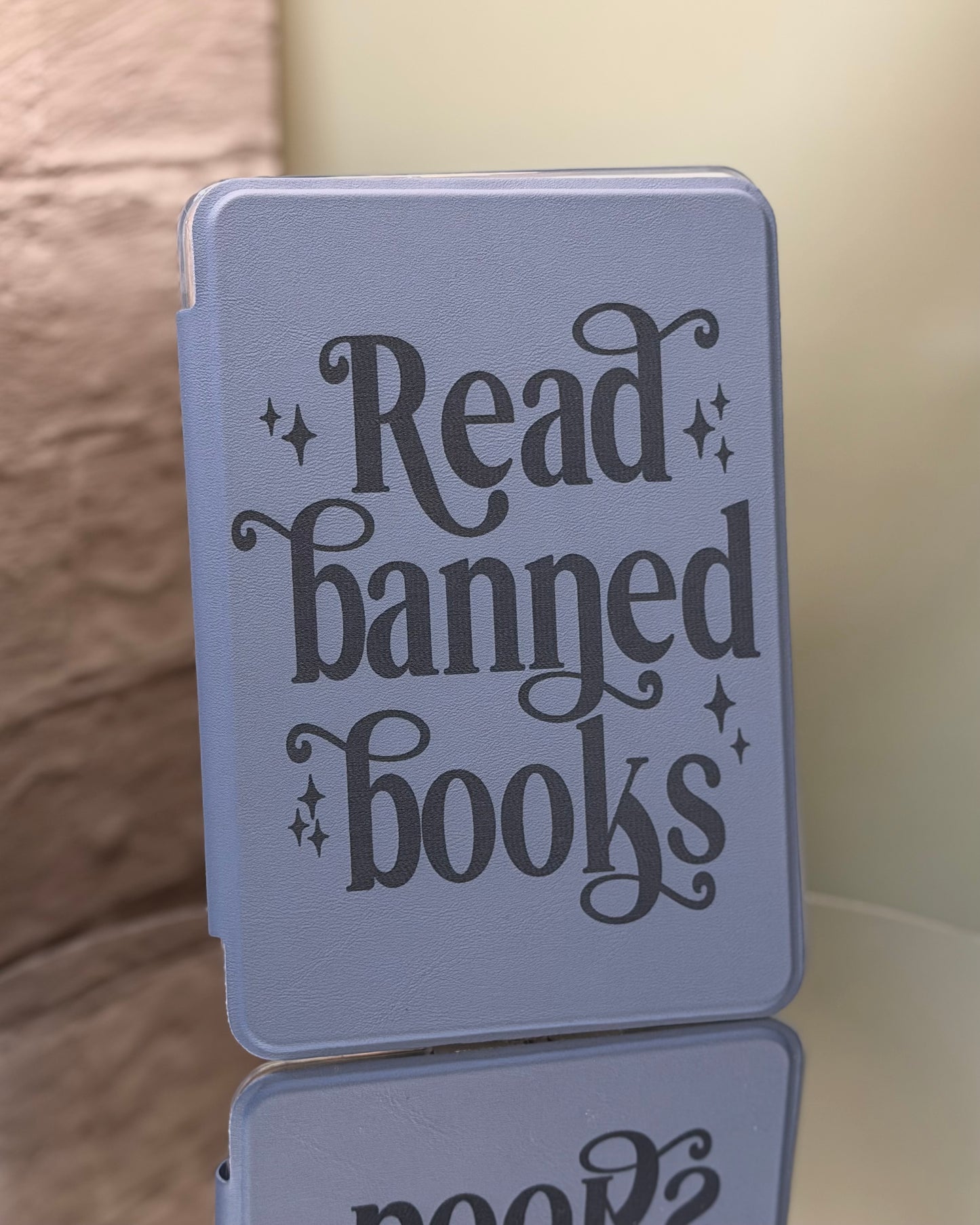Dusty lavender kindle case with 'Read banned books' text on a reflective surface