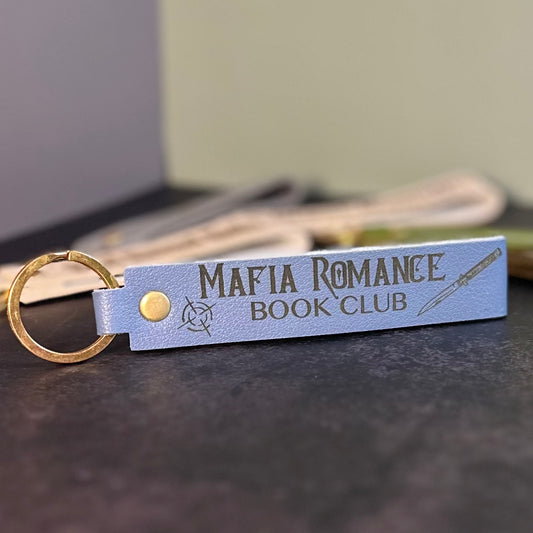 A storm blue faux-leather keychain with 'Mafia romance book club' etched into it.